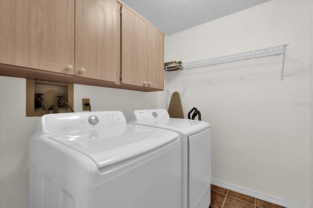 clothes washing area featuring separate washer and dryer, cabinets, and dark tile patterned floors