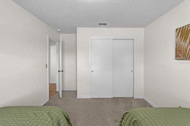 carpeted bedroom with a closet and a textured ceiling