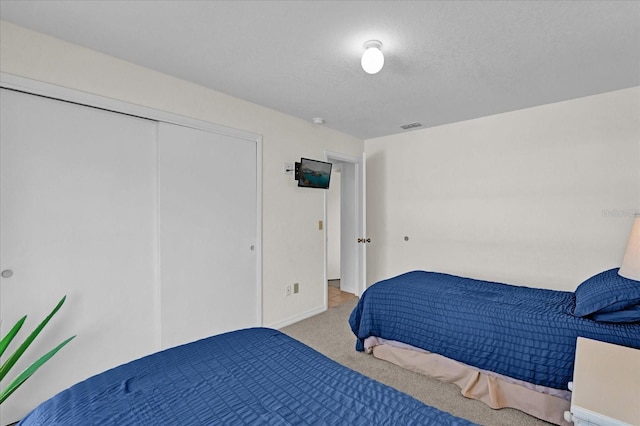 bedroom featuring light carpet and a textured ceiling