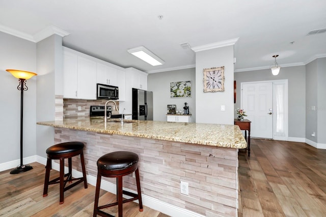 kitchen featuring white cabinetry, sink, light hardwood / wood-style floors, kitchen peninsula, and stainless steel appliances