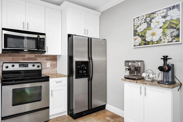 kitchen with stainless steel appliances, white cabinetry, light stone counters, and decorative backsplash