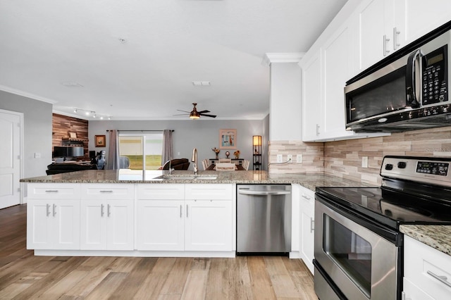 kitchen featuring sink, kitchen peninsula, white cabinets, and appliances with stainless steel finishes