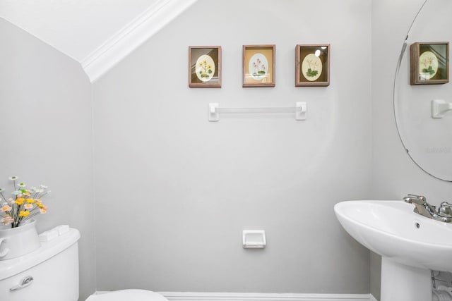 bathroom featuring vaulted ceiling, ornamental molding, toilet, and sink