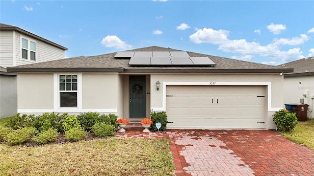 view of front of property with a garage, a front yard, and solar panels