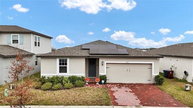 view of front of property featuring a garage, a front yard, and solar panels