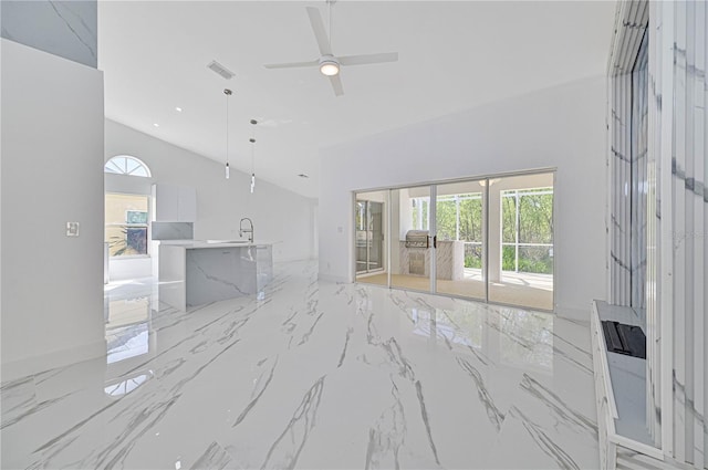 unfurnished living room with ceiling fan, sink, and high vaulted ceiling