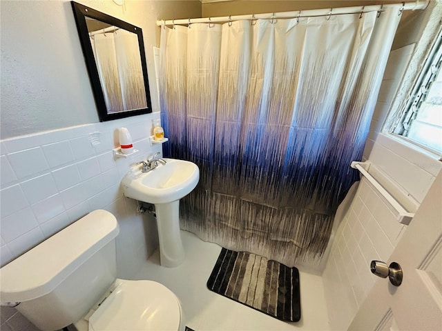 bathroom with tile walls, toilet, and a shower with shower curtain