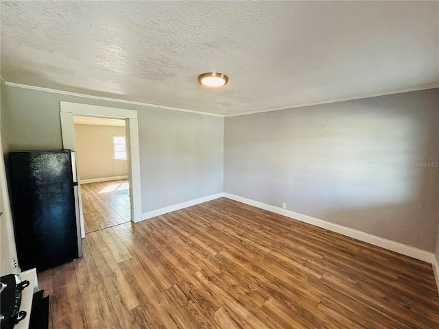 spare room featuring hardwood / wood-style flooring, ornamental molding, and a textured ceiling