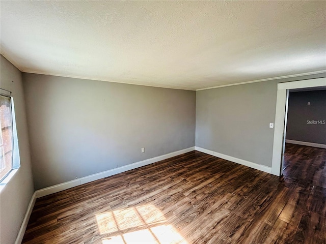 empty room with a textured ceiling and dark hardwood / wood-style flooring