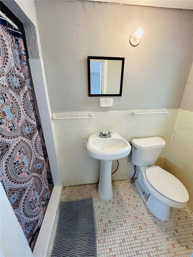 bathroom with toilet, sink, a shower with curtain, tile walls, and tile patterned flooring