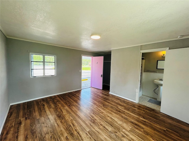 unfurnished room with crown molding, dark wood-type flooring, and a textured ceiling