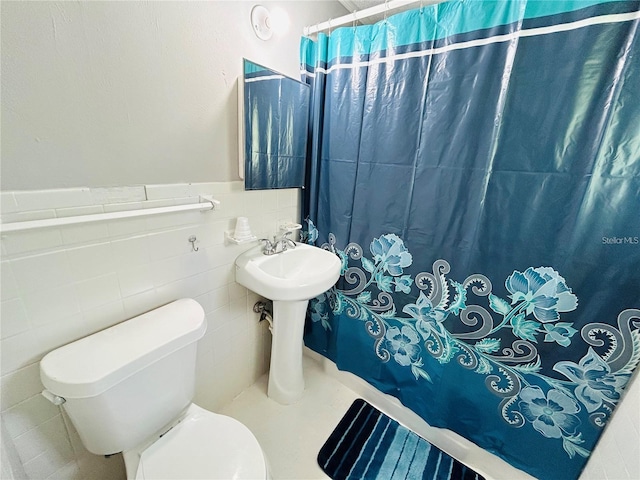 bathroom featuring toilet, sink, and tile walls