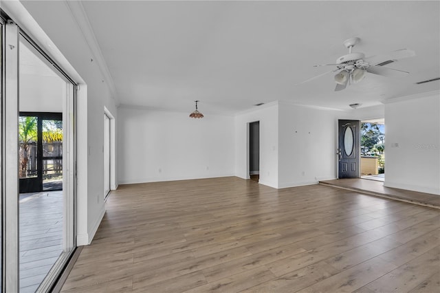 spare room featuring crown molding, plenty of natural light, and light wood-type flooring