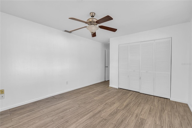 unfurnished bedroom featuring ceiling fan, a closet, and light wood-type flooring