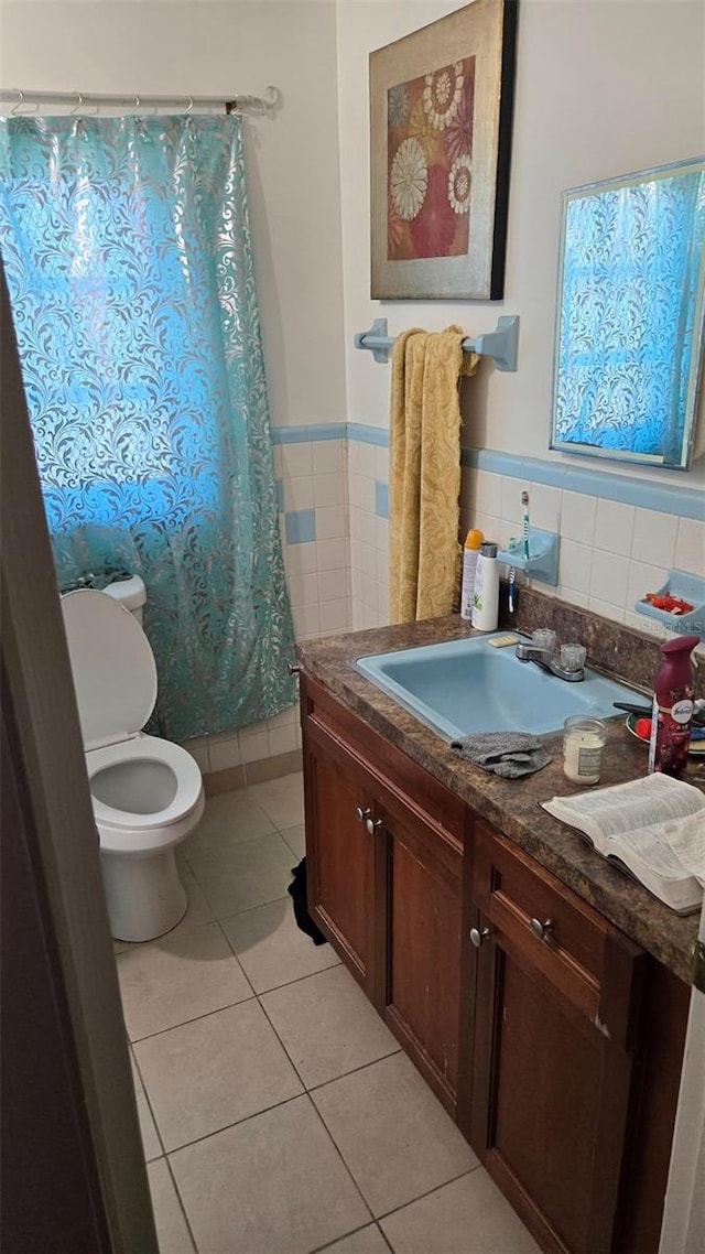 bathroom with tile walls, vanity, toilet, tile patterned floors, and a shower with curtain