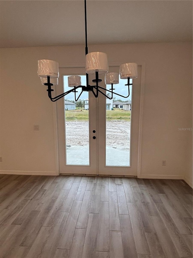 doorway to outside with hardwood / wood-style flooring and a notable chandelier