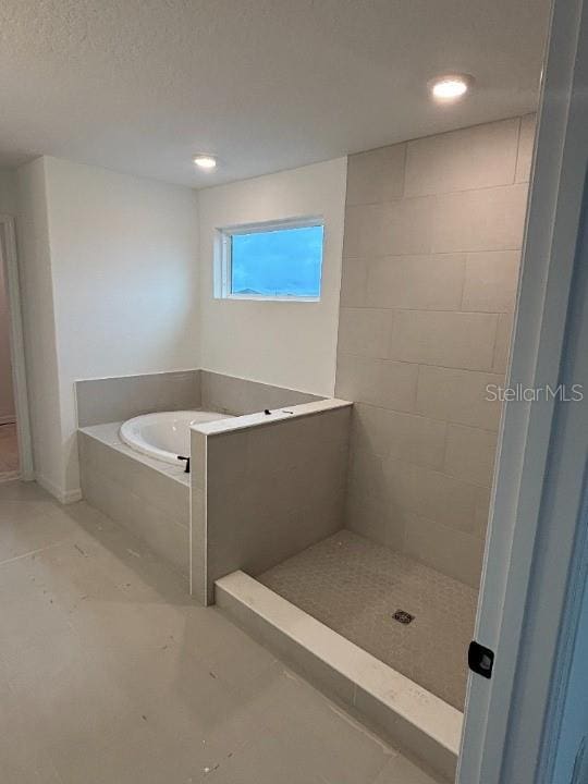 bathroom featuring separate shower and tub and a textured ceiling