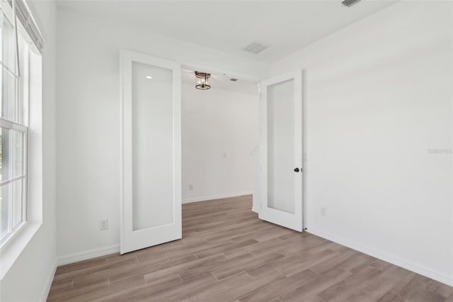 unfurnished room featuring baseboards, visible vents, and light wood finished floors