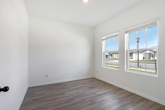 spare room with baseboards and wood finished floors