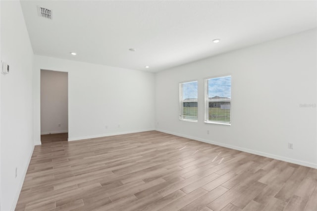 unfurnished room featuring baseboards, light wood-style flooring, visible vents, and recessed lighting