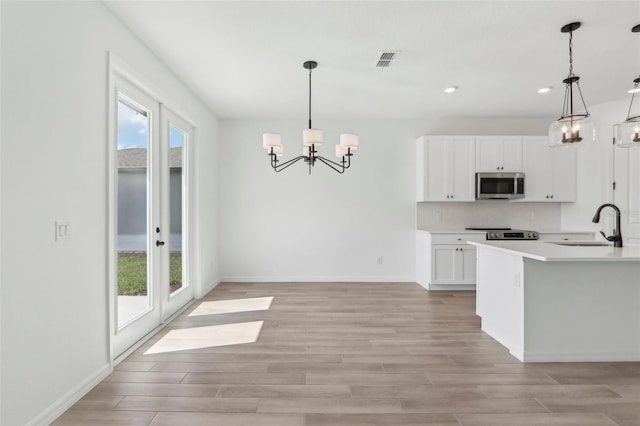 kitchen featuring appliances with stainless steel finishes, a wealth of natural light, a sink, and an inviting chandelier