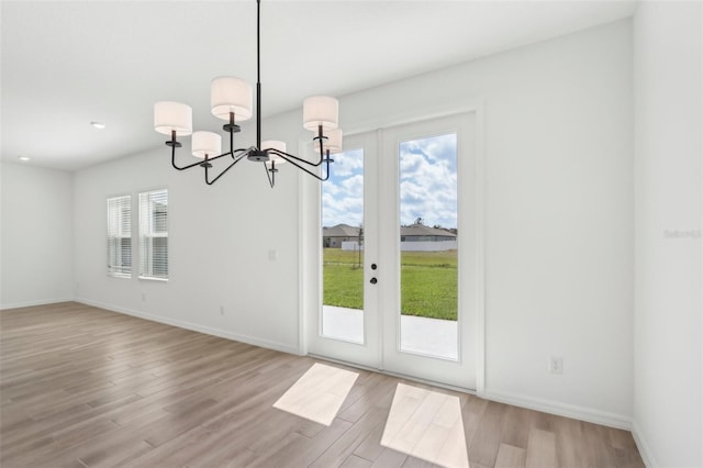 interior space featuring a chandelier, light wood-type flooring, and baseboards