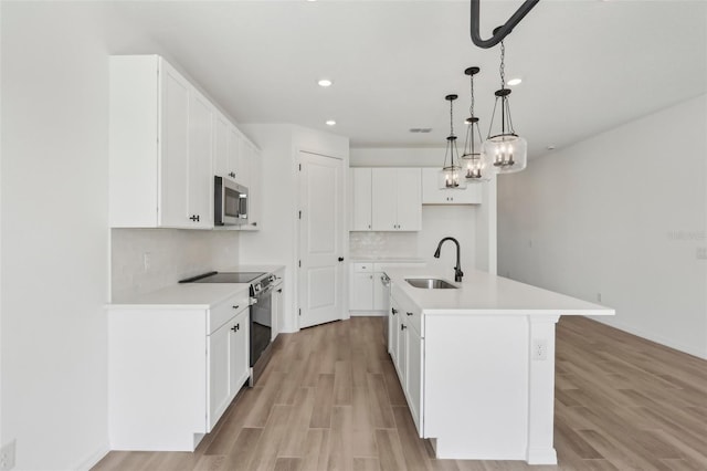 kitchen with light wood finished floors, stainless steel appliances, tasteful backsplash, and a sink