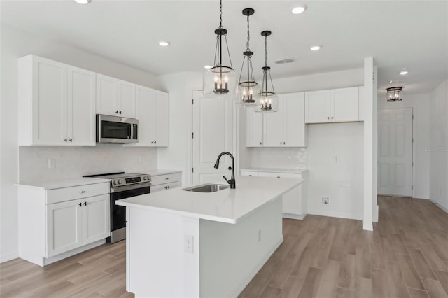 kitchen with visible vents, light wood-style flooring, appliances with stainless steel finishes, white cabinetry, and a sink