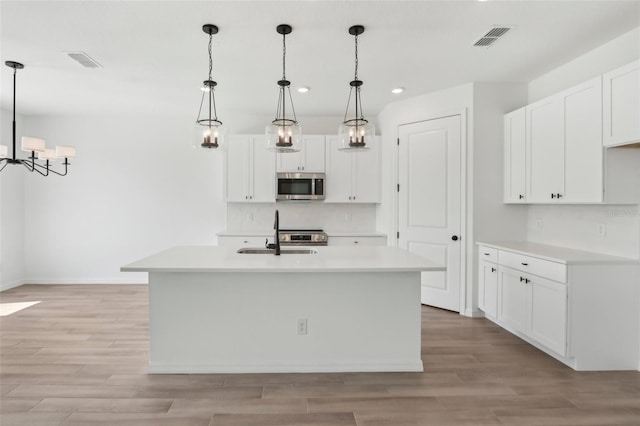 kitchen with visible vents, stainless steel microwave, light countertops, and a sink