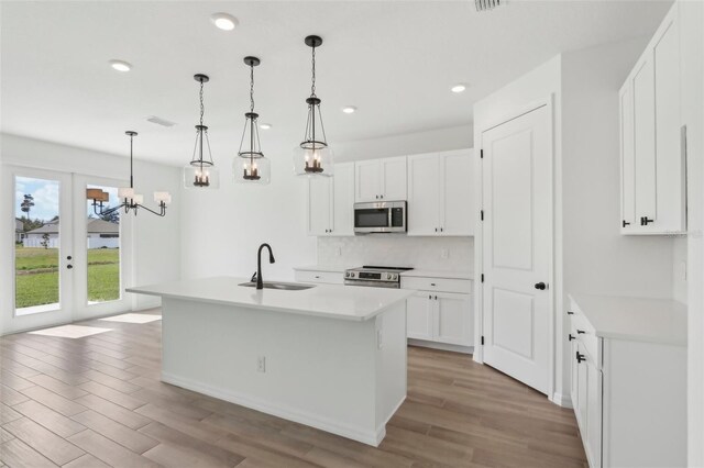 kitchen featuring appliances with stainless steel finishes, light wood-type flooring, a sink, and tasteful backsplash