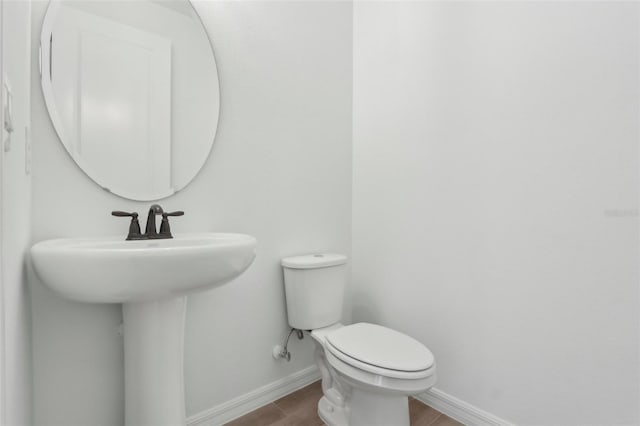 bathroom featuring a sink, toilet, and baseboards