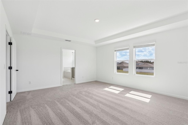 unfurnished bedroom with a raised ceiling, light colored carpet, visible vents, and baseboards