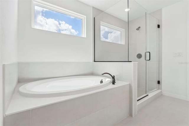 bathroom featuring a healthy amount of sunlight, a stall shower, and a bath