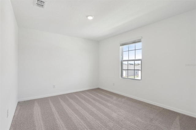 carpeted spare room with visible vents and baseboards