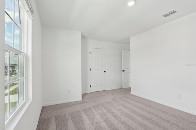 carpeted spare room with visible vents and baseboards