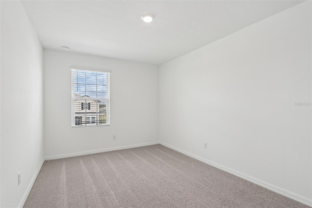 empty room with light colored carpet and baseboards