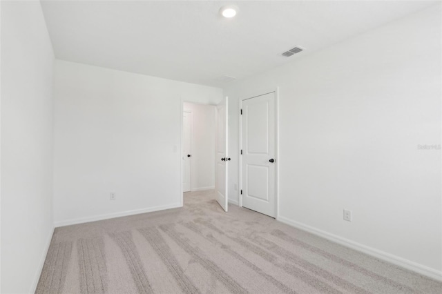 carpeted spare room featuring visible vents and baseboards