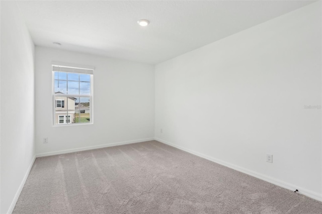 carpeted spare room featuring baseboards