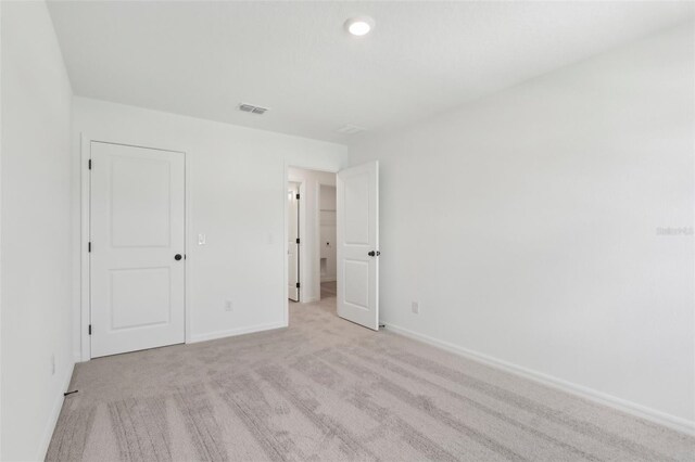 unfurnished bedroom featuring light colored carpet, visible vents, and baseboards