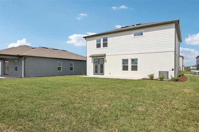 rear view of property with french doors, stucco siding, a lawn, and central AC unit