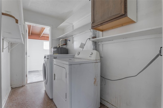 clothes washing area featuring cabinets, water heater, and washing machine and clothes dryer