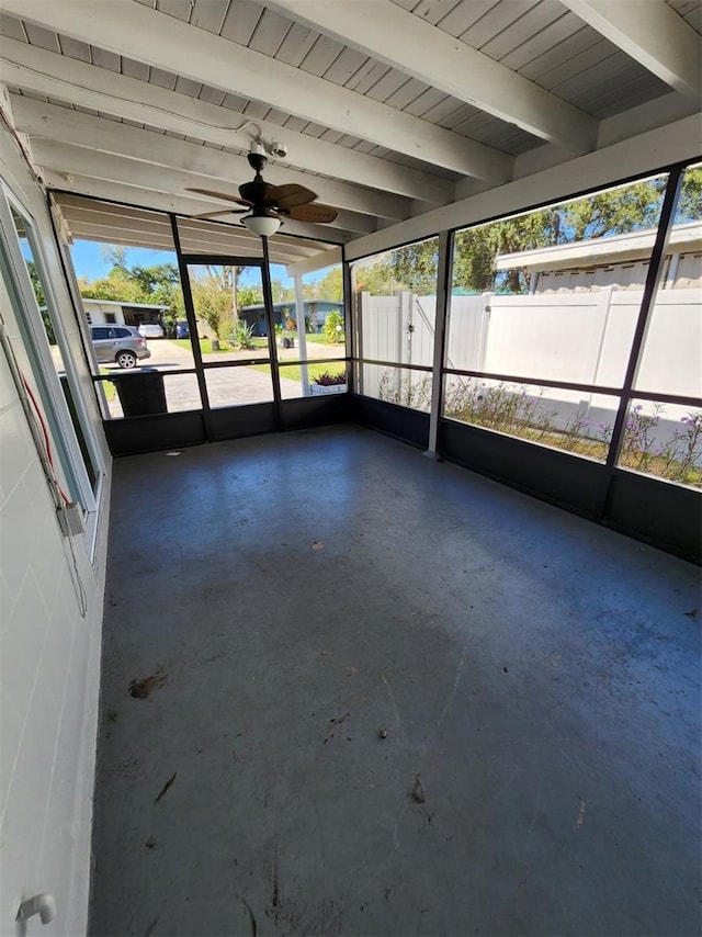 unfurnished sunroom with ceiling fan, beam ceiling, and a wealth of natural light