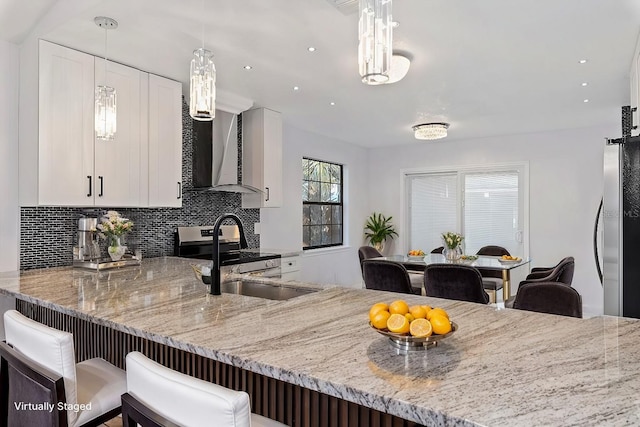 kitchen featuring white cabinetry, wall chimney range hood, tasteful backsplash, and sink