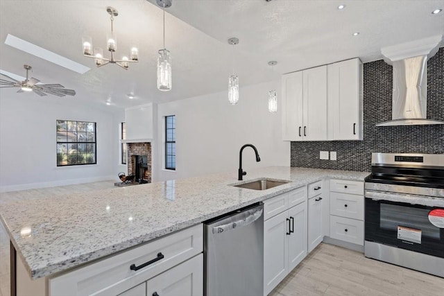 kitchen with white cabinetry, stainless steel appliances, sink, and wall chimney range hood