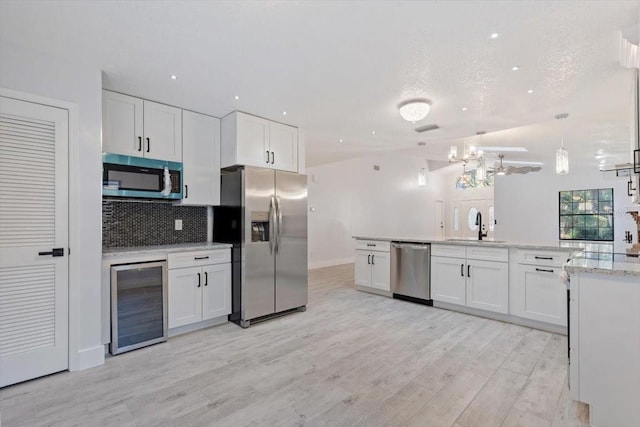 kitchen featuring wine cooler, white cabinetry, stainless steel appliances, and decorative light fixtures