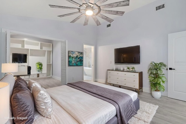 bedroom with ensuite bathroom, a closet, ceiling fan, and light wood-type flooring