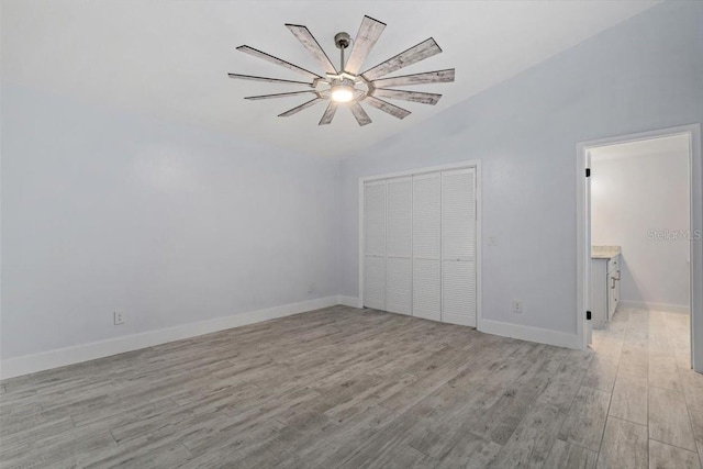 unfurnished bedroom featuring vaulted ceiling, ceiling fan, light hardwood / wood-style floors, and a closet