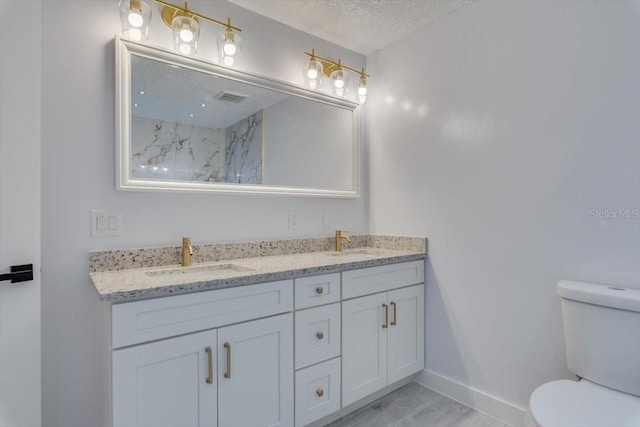 bathroom with vanity, toilet, and a textured ceiling