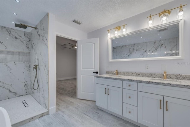 bathroom with tiled shower, wood-type flooring, a textured ceiling, and vanity