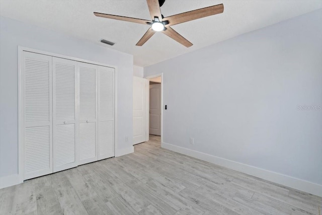 unfurnished bedroom featuring a closet, a textured ceiling, ceiling fan, and light hardwood / wood-style flooring